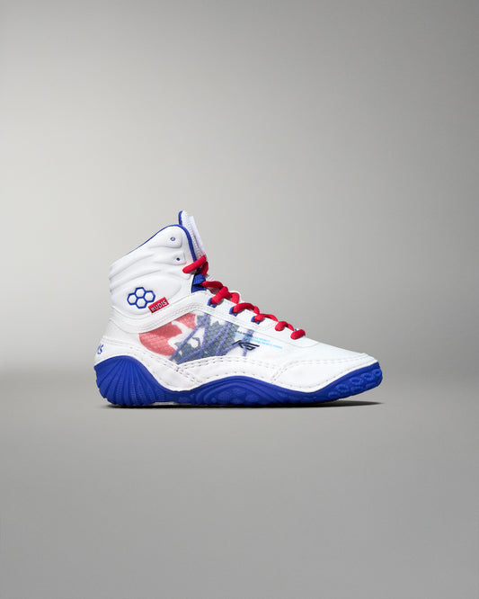 Side view of a white RUDIS KS Infinity Edge Wrestling Shoe featuring a red, white, and blue USA flag-inspired design, red laces, blue outsole, RUDIS hexagon logo near the ankle, and official USA Wrestling branding