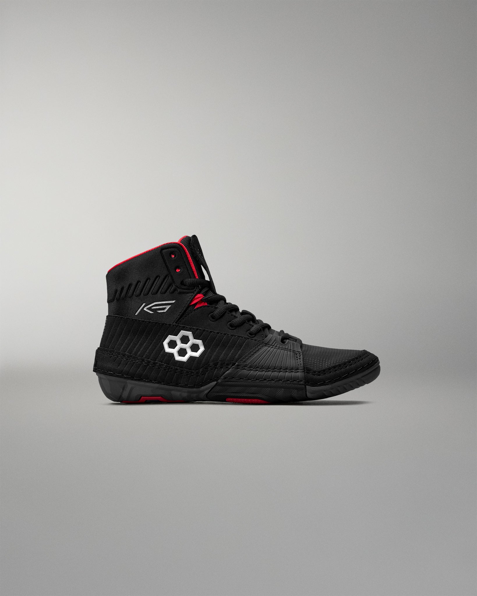 Black wrestling shoes with red accents on a gray background