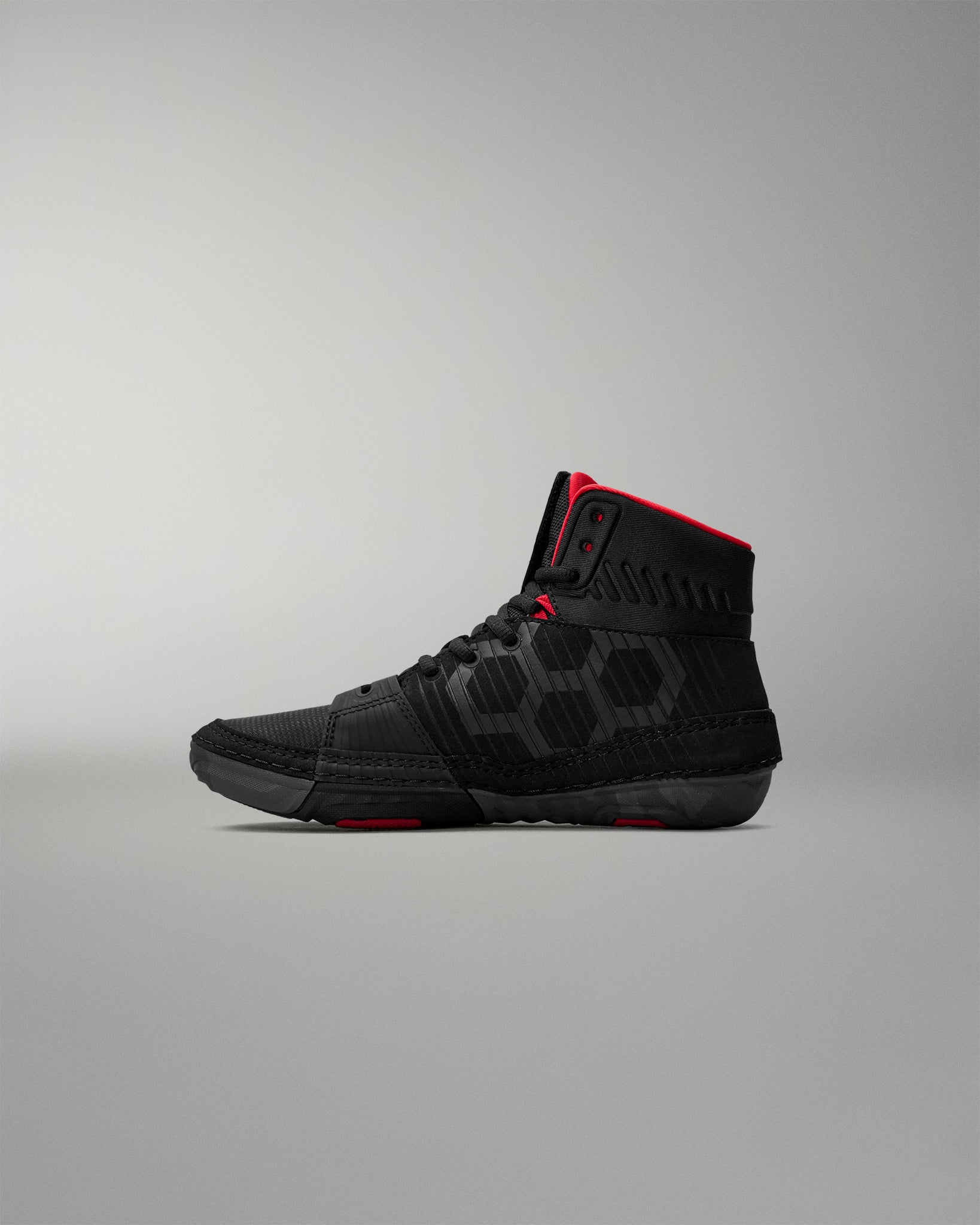 Black wrestling shoes with red accents on a gray background