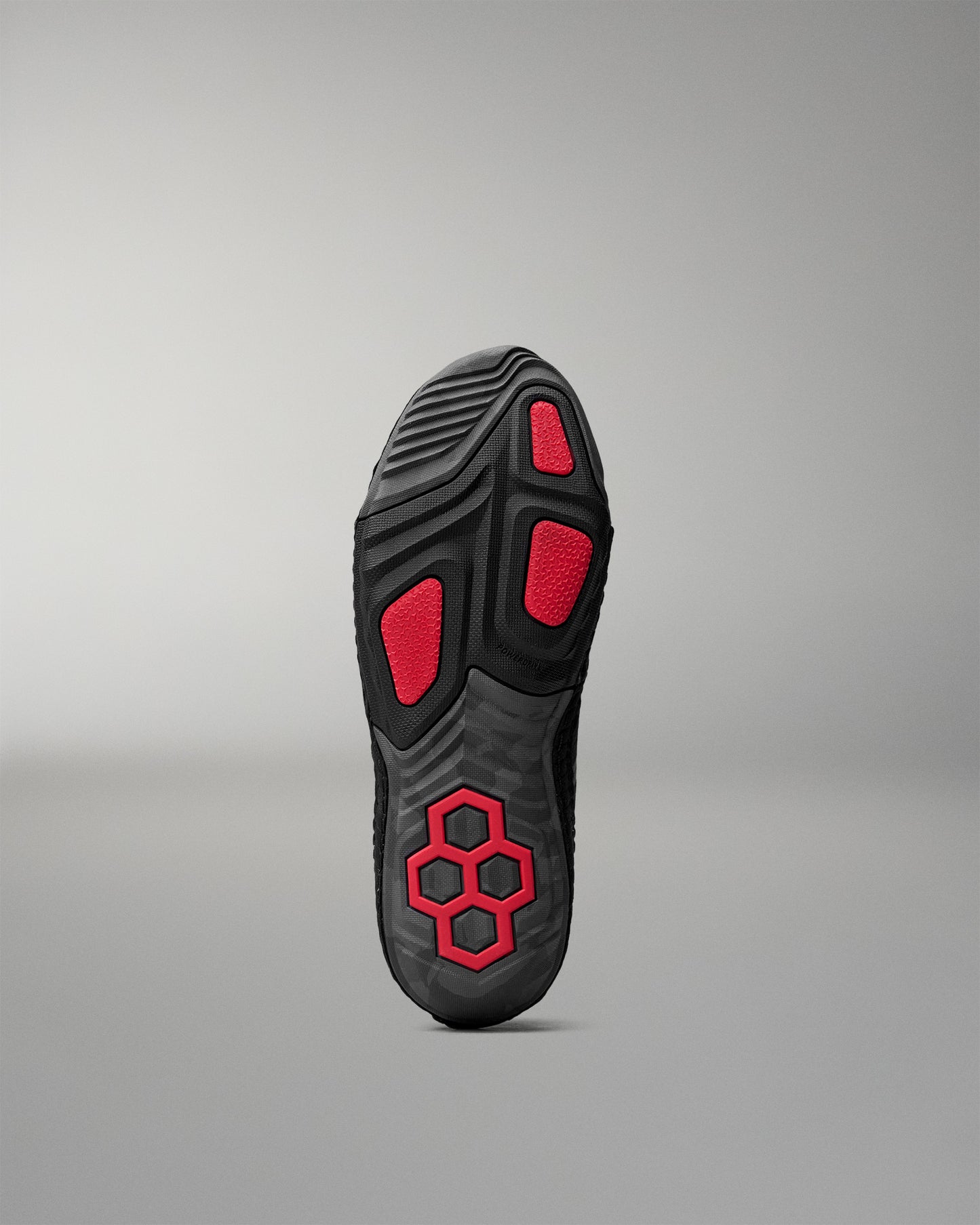 Black wrestling shoe sole with red accents on a gray background