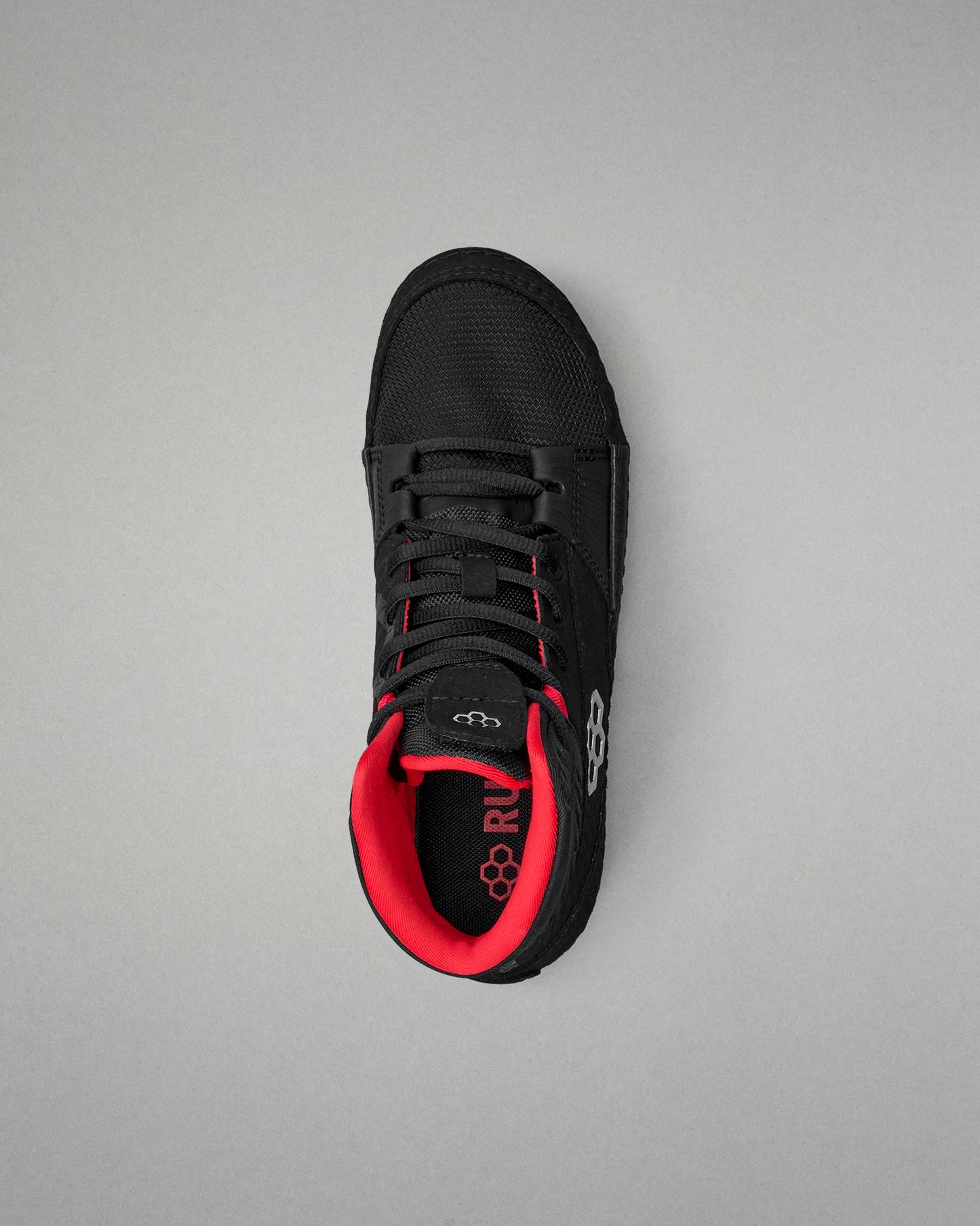 Black wrestling shoe with red interior on a gray background