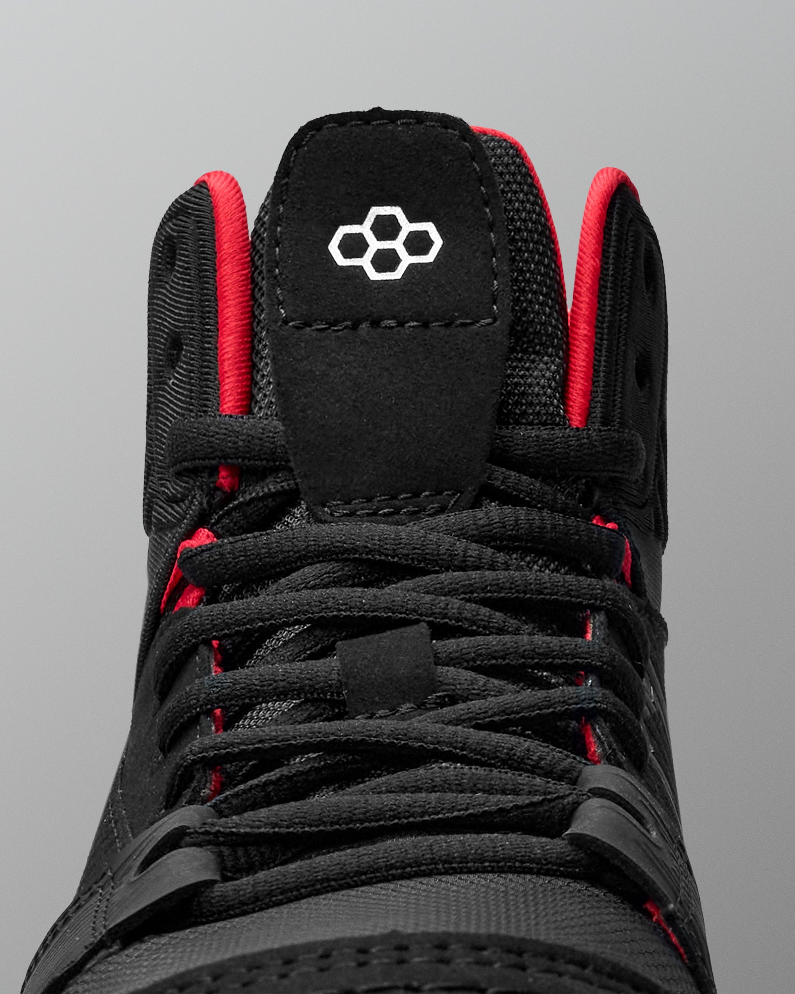 Black wrestling shoe with red accents on a gray background