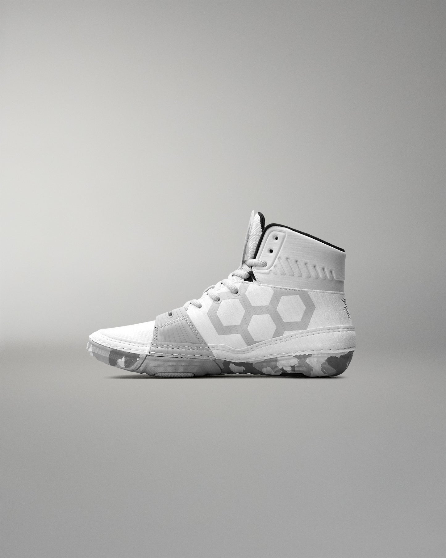White wrestling shoe with geometric patterns on a gray background