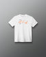 A white short-sleeve crewneck t-shirt with a graphic print on the chest, featuring an orange script signature and small black text, displayed against a dark gray gradient background.