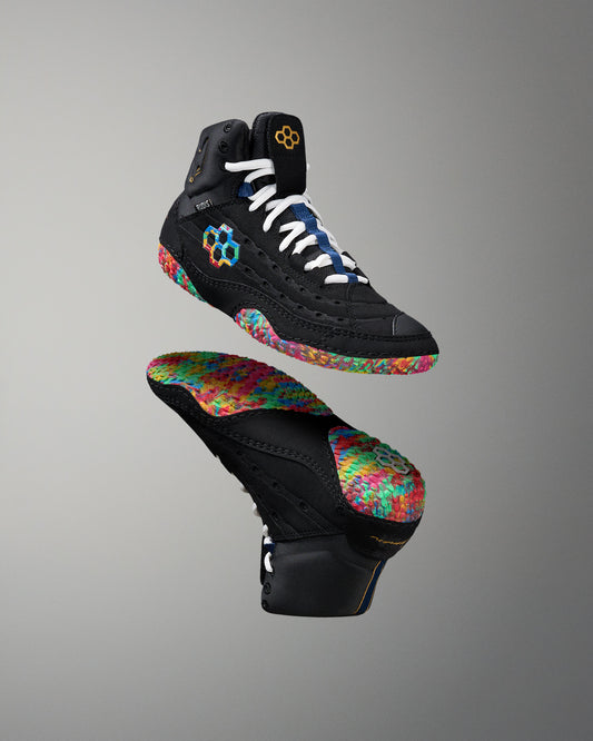 Black wrestling shoes with colorful soles on a gray background
