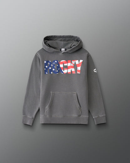 A gray pullover hoodie with a front kangaroo pocket and a large 'ROCKY' graphic across the chest in an American flag pattern. The word 'ROCKY' is filled with blue and white stars on the left side and red and white stripes on the right side.