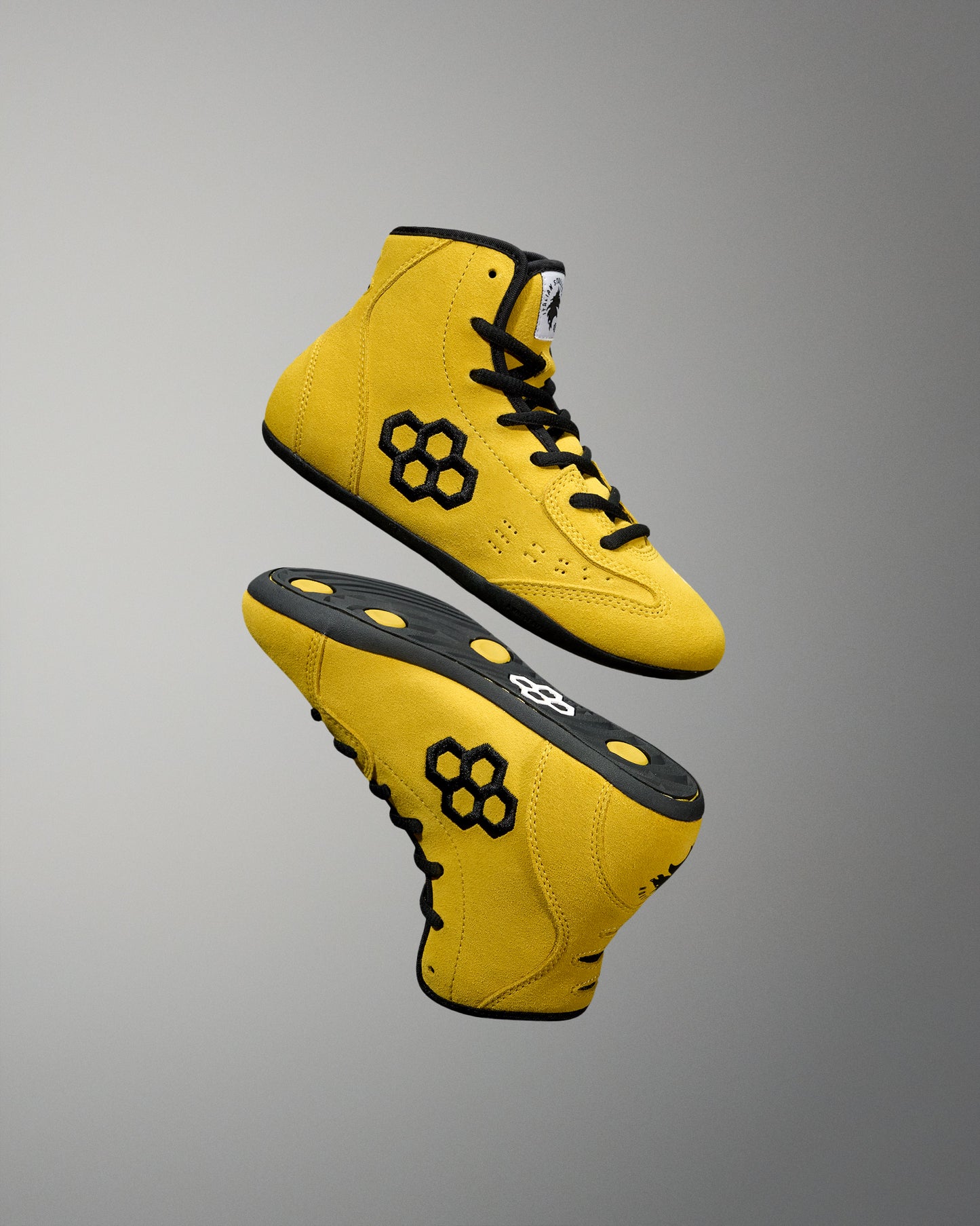 Yellow wrestling shoes with black accents on a gray background