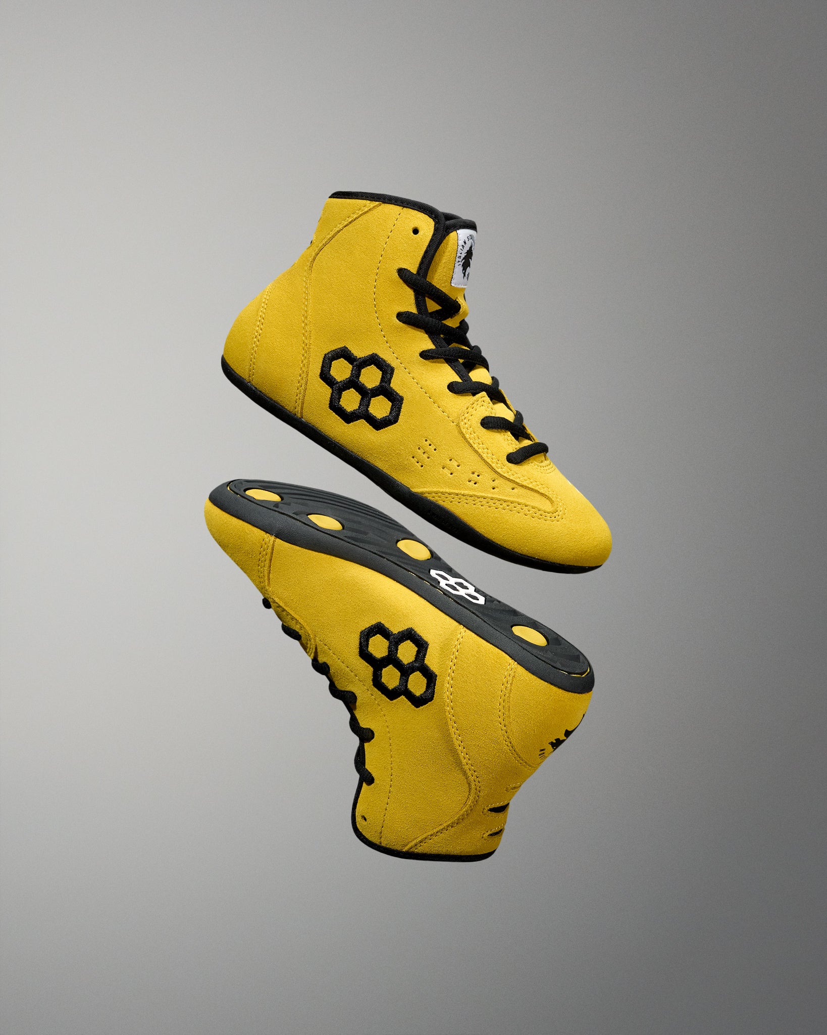 Yellow wrestling shoes with black accents on a gray background