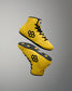Yellow wrestling shoes with black accents on a gray background