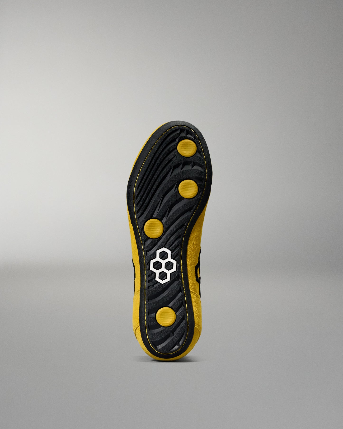 Black and yellow wrestling shoes sole with a brand logo on a gray background