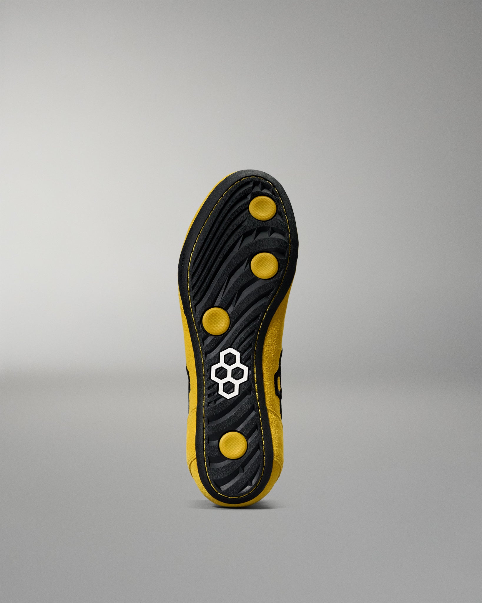 Black and yellow wrestling shoes sole with a brand logo on a gray background