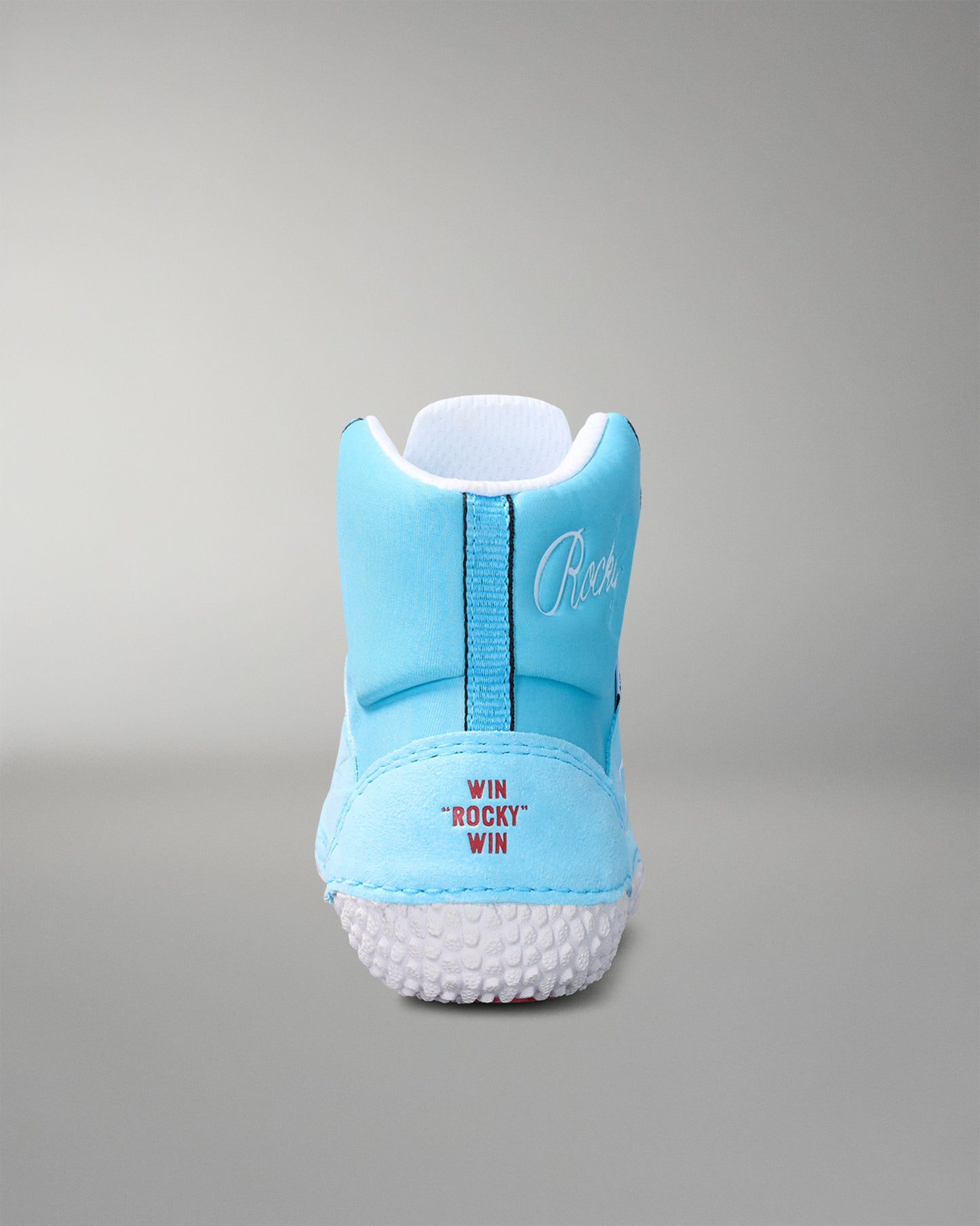 Light blue wrestling shoe with white sole on a gray background
