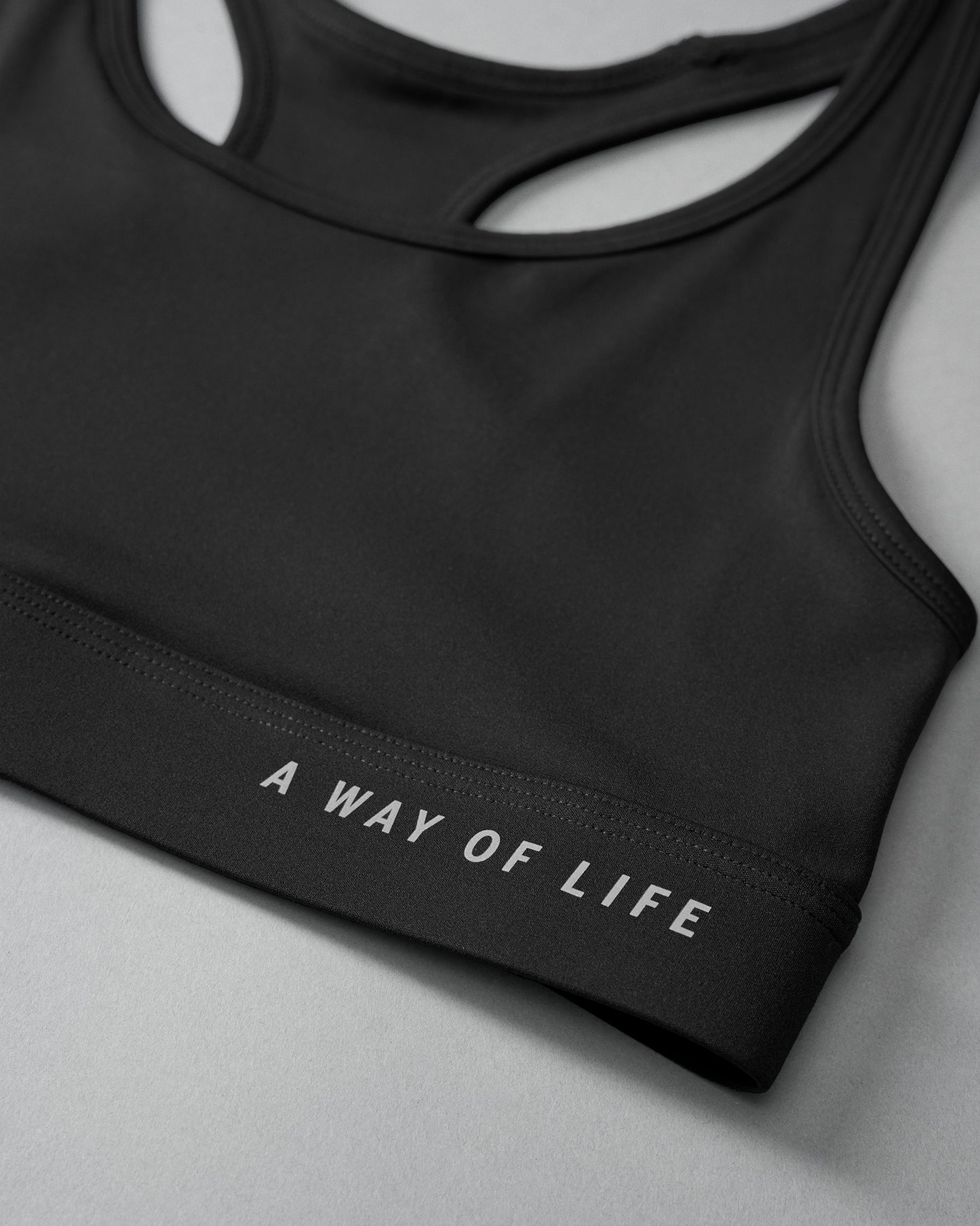 Black sports bra with 'A Way of Life' text on a gray background