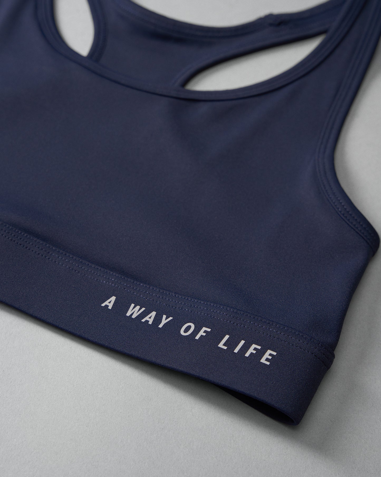 Navy blue sports bra with 'A Way of Life' text on a light gray background