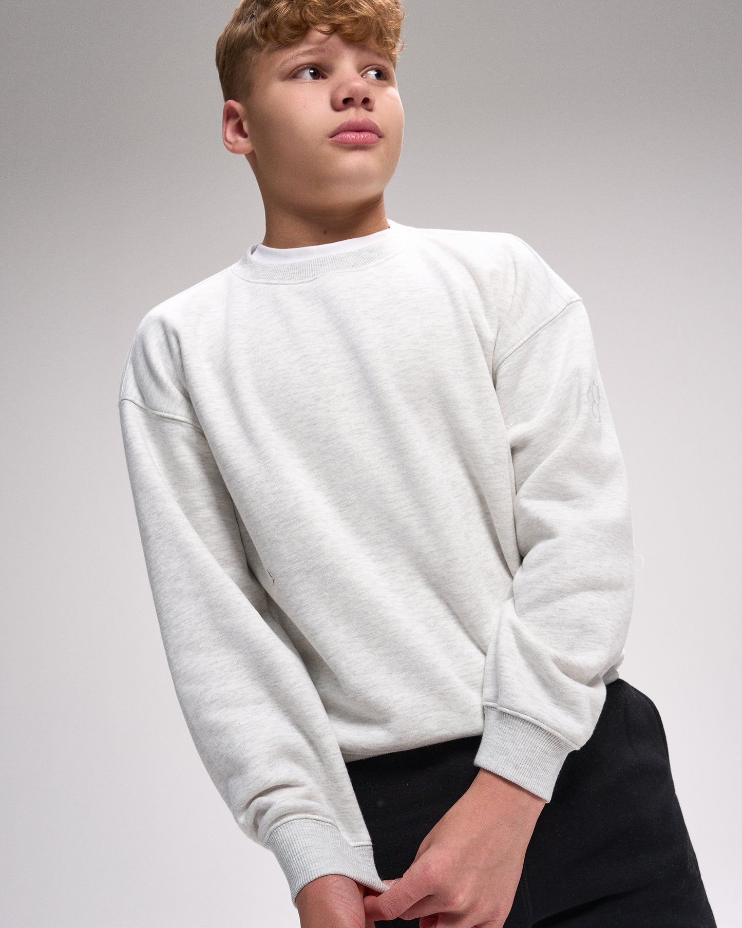 Person wearing a light gray sweatshirt on a plain background