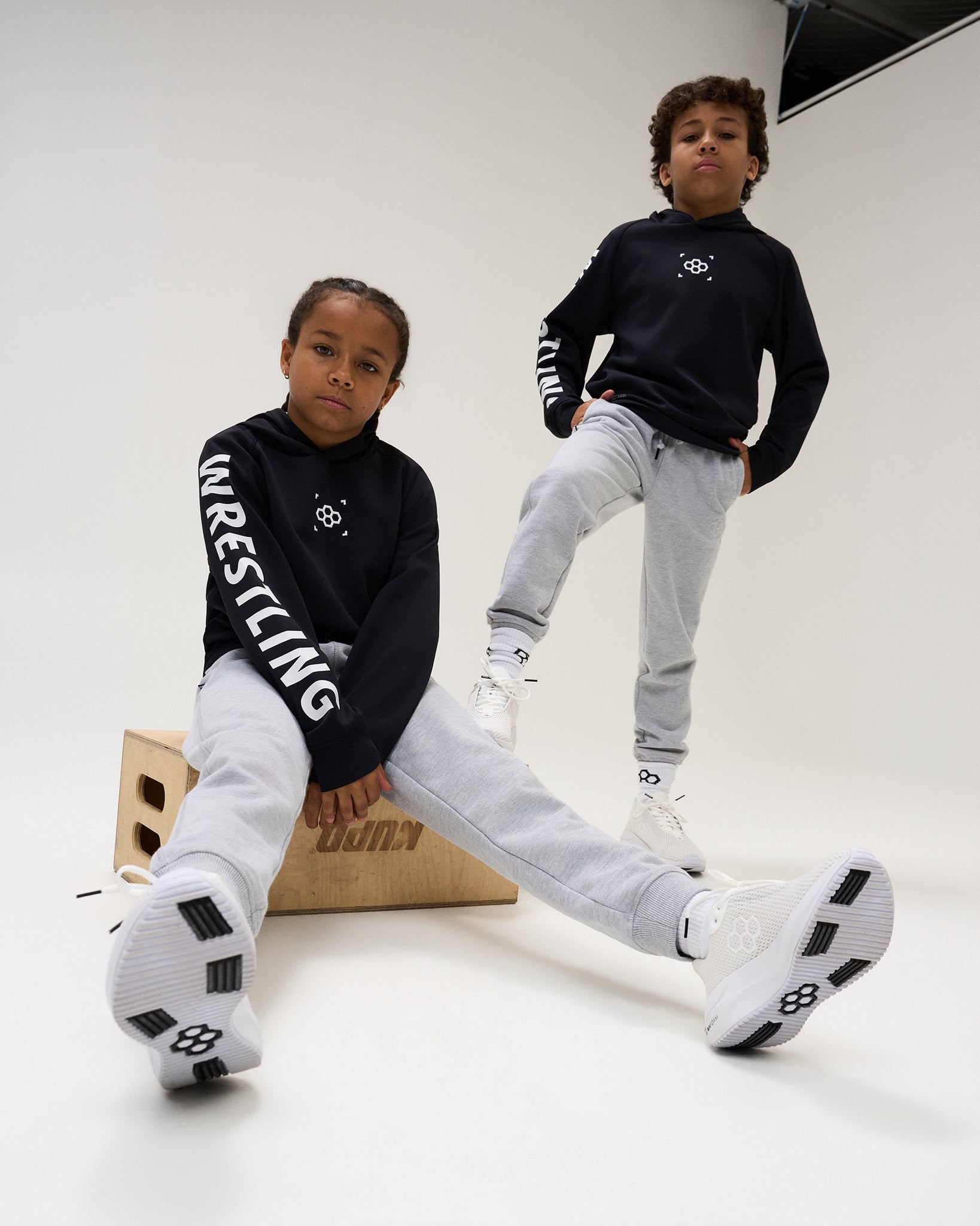 RUDIS Wrestling Youth COOL FEEL Hoodie in Black with bold white WRESTLING sleeve graphics and RUDIS chest branding, paired with grey joggers and RUDIS footwear.
