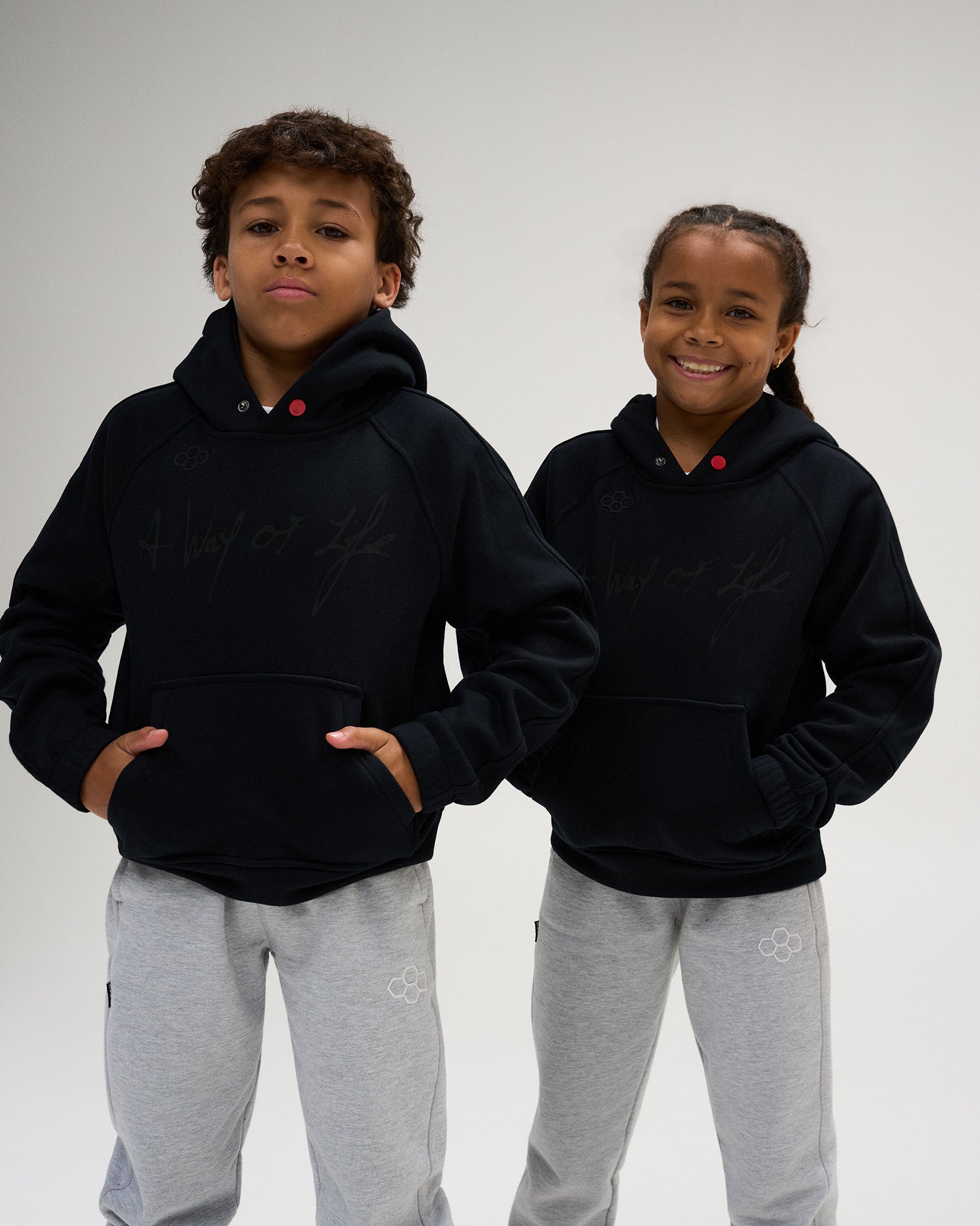 RUDIS A Way of Life Youth Tech Fleece Hoodie in Black, featuring tonal RUDIS branding, script chest graphic, kangaroo pocket, and snap-detail hood, paired with grey joggers.