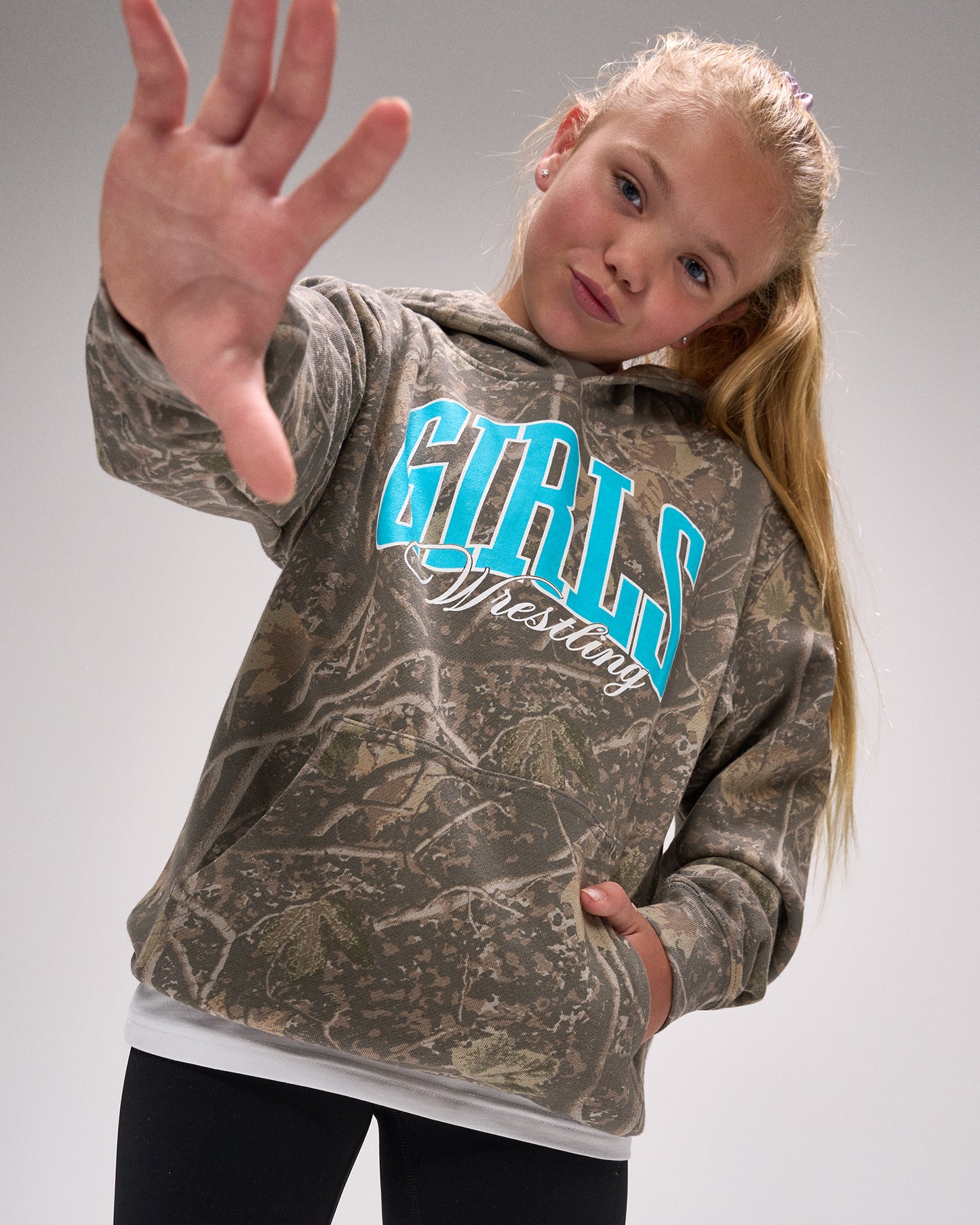 Girl wearing a camouflage hoodie with 'Girls Wrestling' text on a gray background