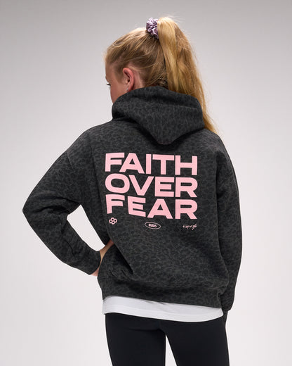 Person wearing a dark hoodie with 'Faith Over Fear' text on the back against a gray background