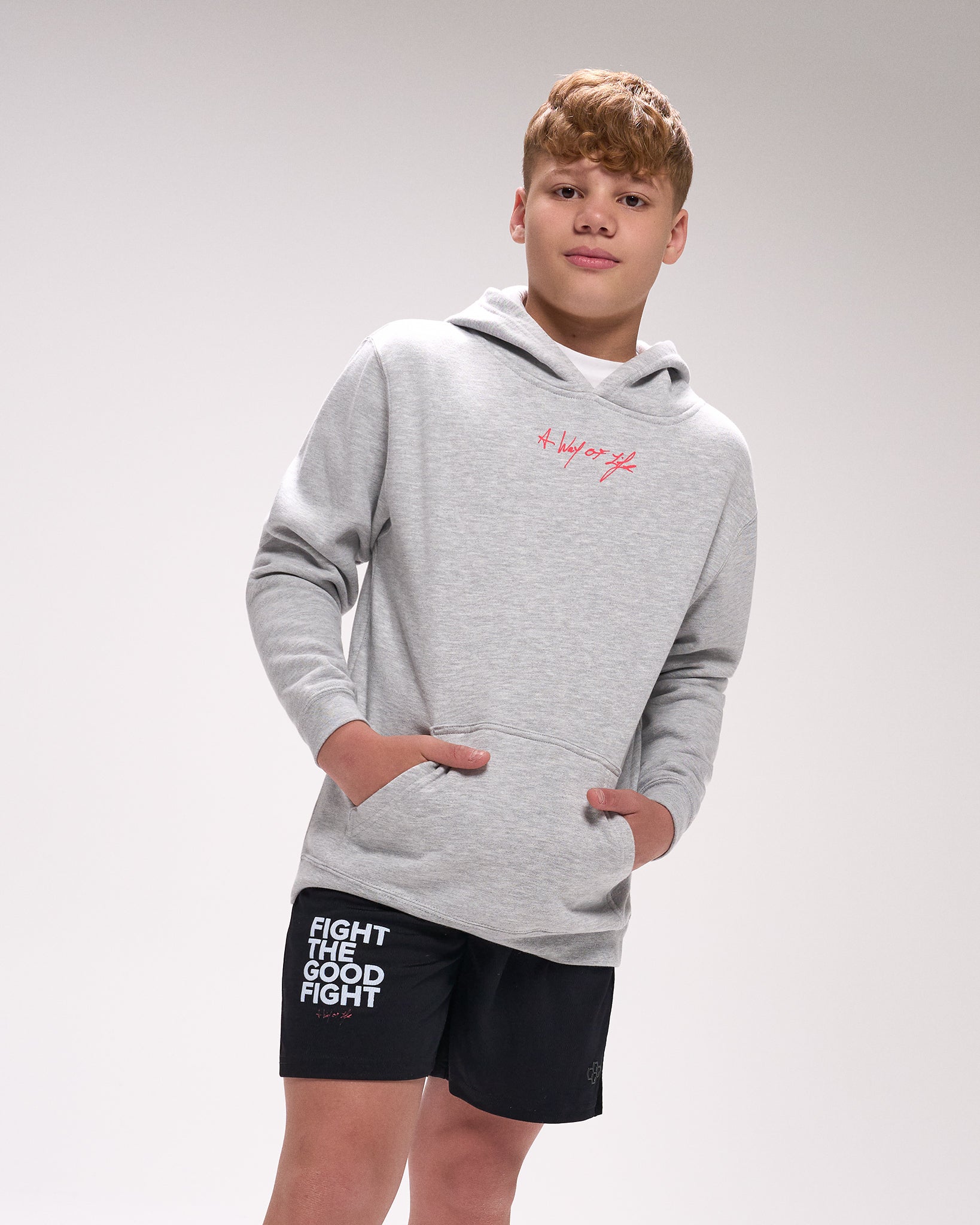 Person wearing a gray hoodie and black shorts with text on a plain background
