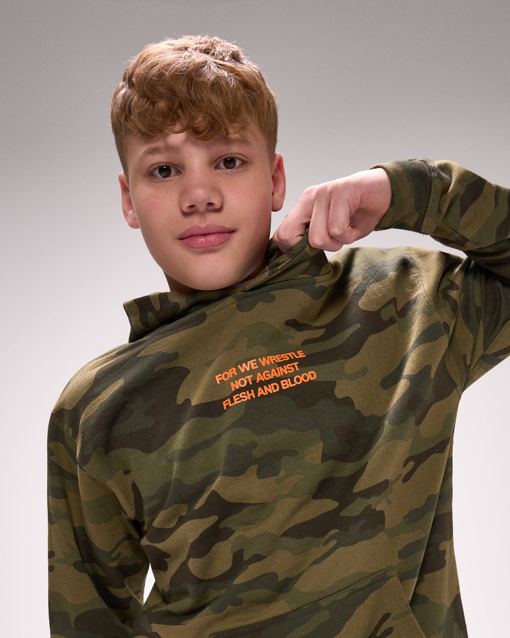 Person wearing a camouflage hoodie with text on a gray background