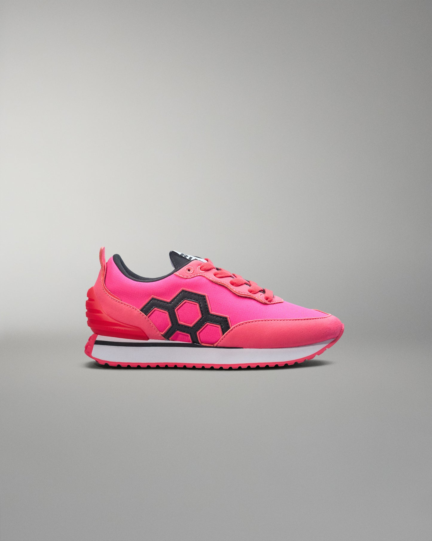 Pink sneaker with black accents on a gray background