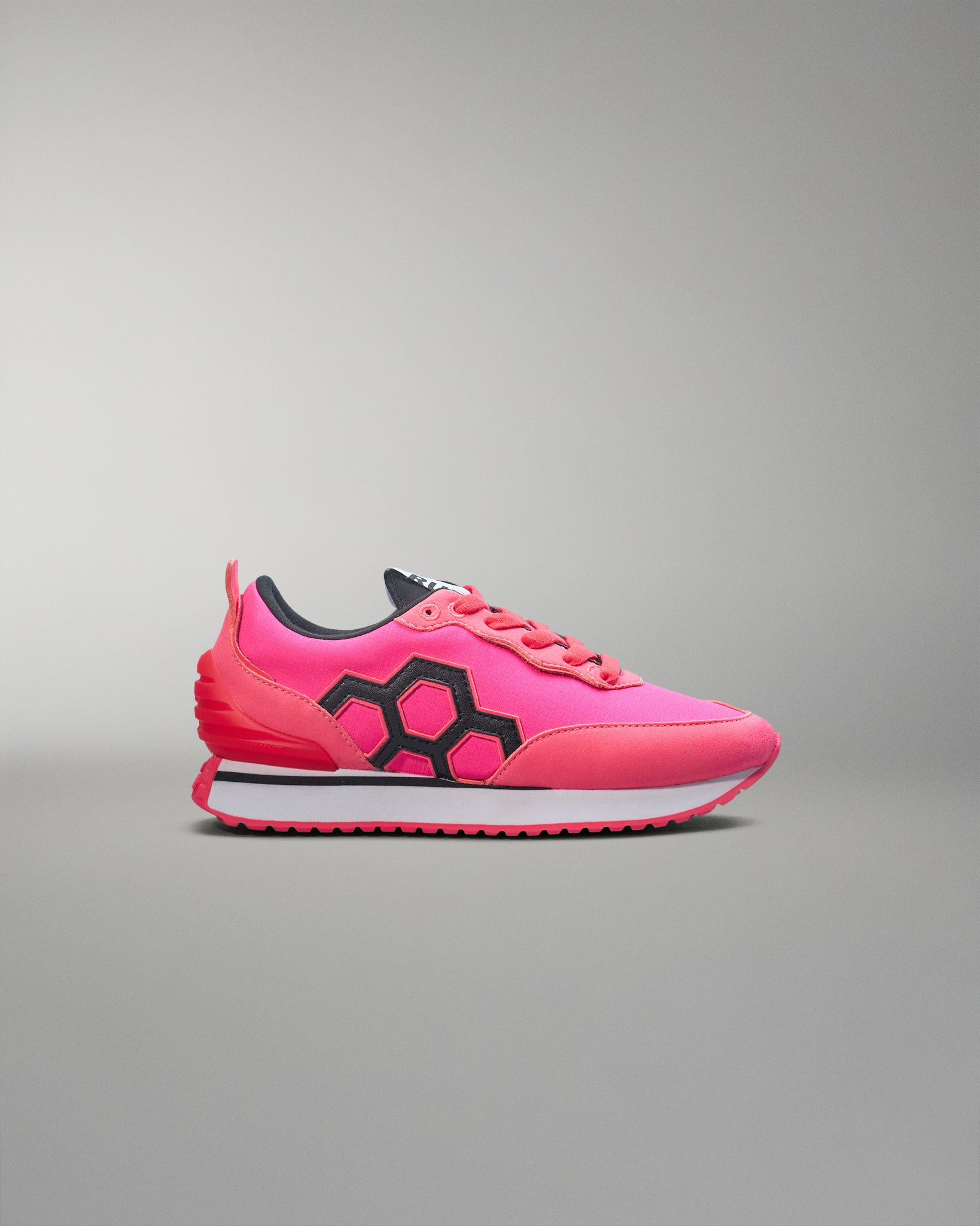 Pink sneaker with black accents on a gray background