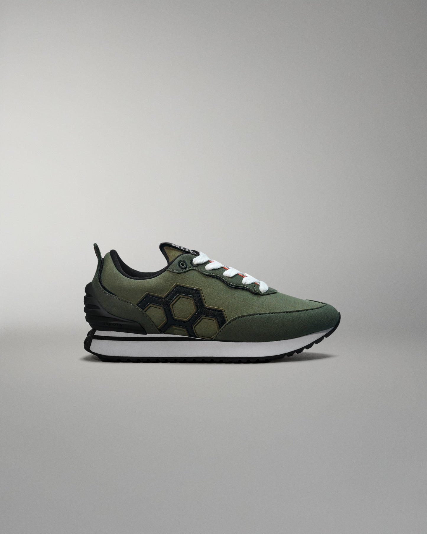 Green sneaker with white sole on a gray background