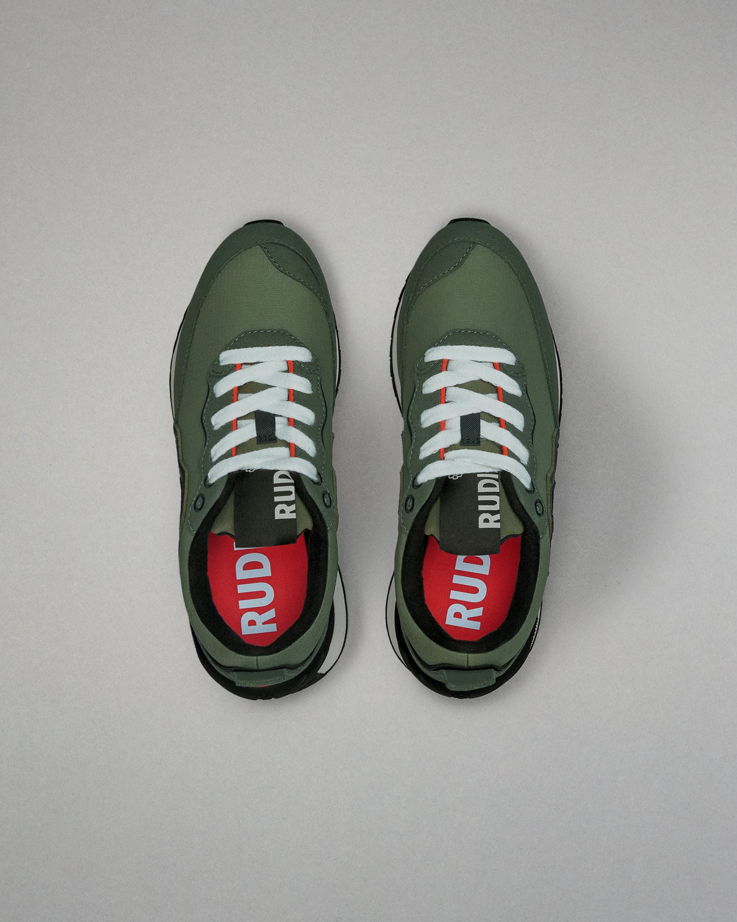Green running shoes with white laces on a gray background