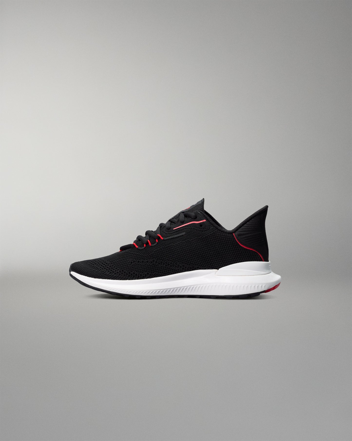 Black running shoe with white sole on a gray background