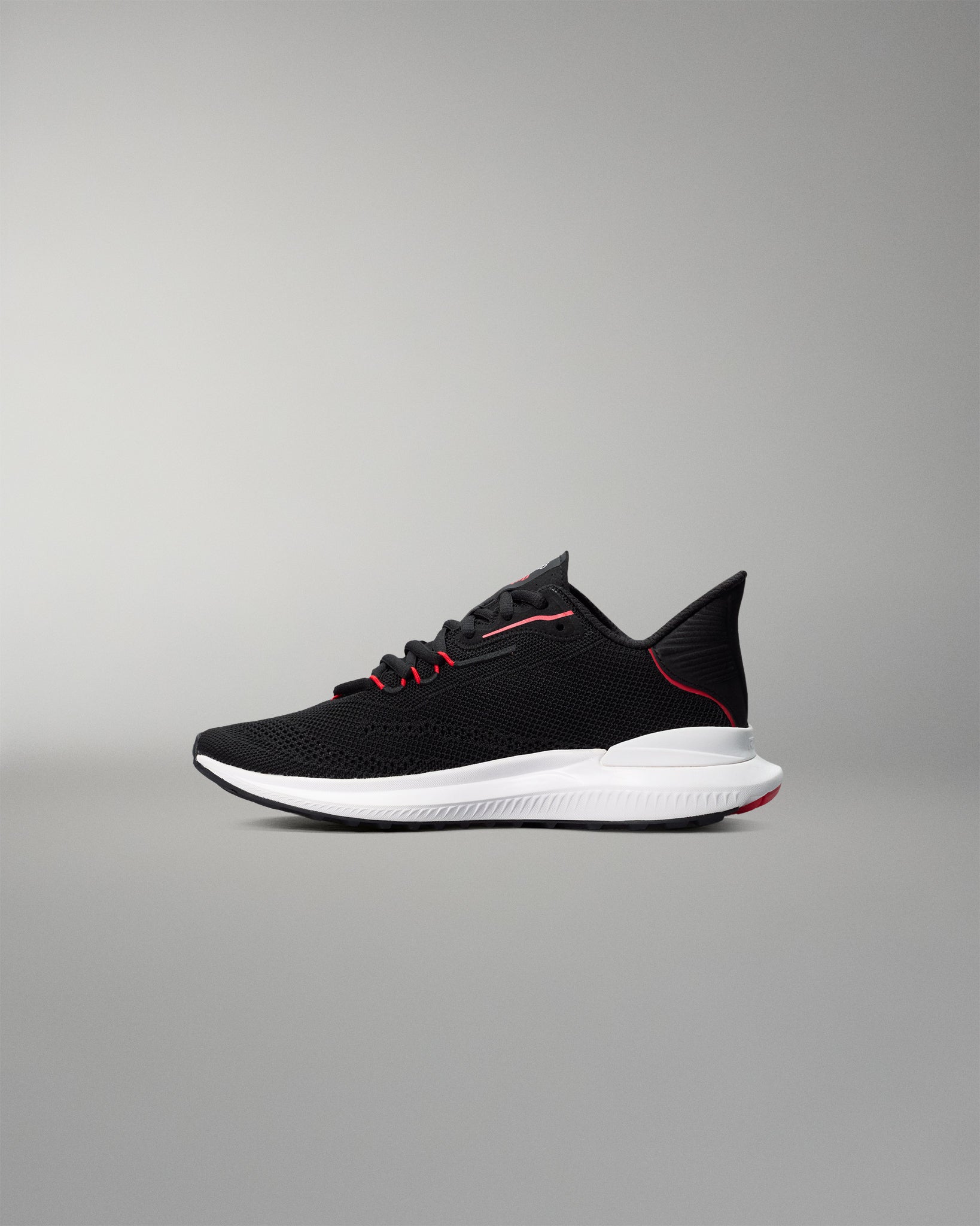 Black running shoe with white sole on a gray background