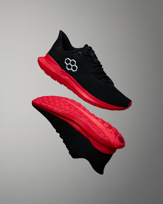 Black and red running shoes with a brand logo on a gray background