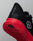 Close-up rear angle of a black RUDIS training shoe with a red outsole and midsole. Features the phrase ‘A WAY OF LIFE’ on the black heel tab, white hexagon logo on the side, and RUDIS branding on the sole.