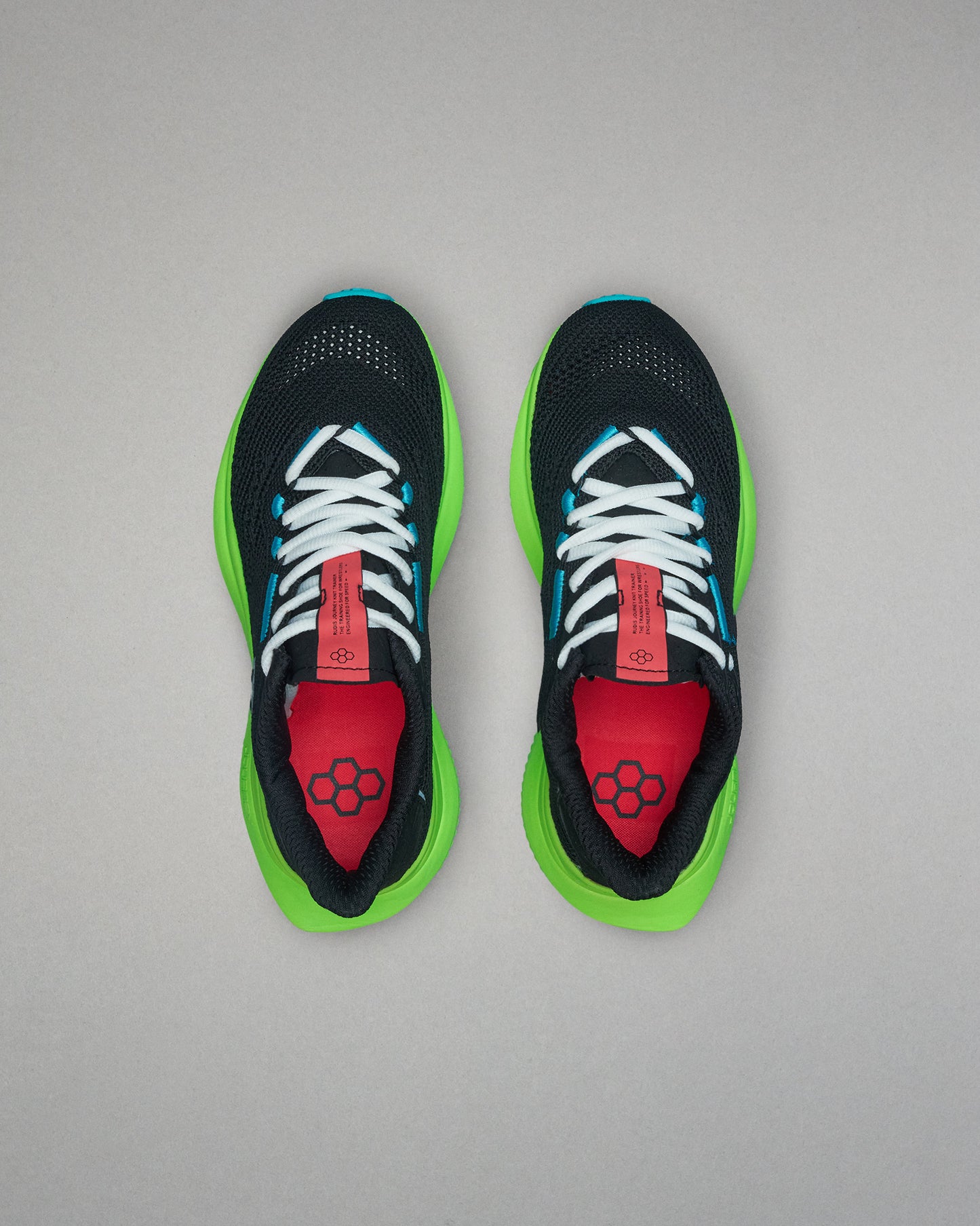 Black running shoes with green soles and red accents on a gray background