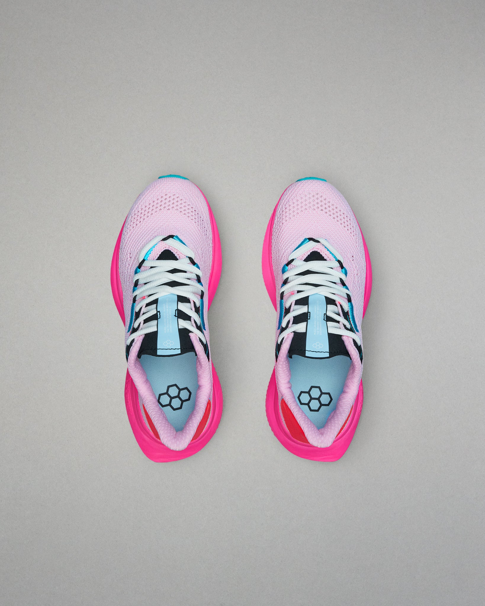 Pink running shoes with black and blue accents on a gray background