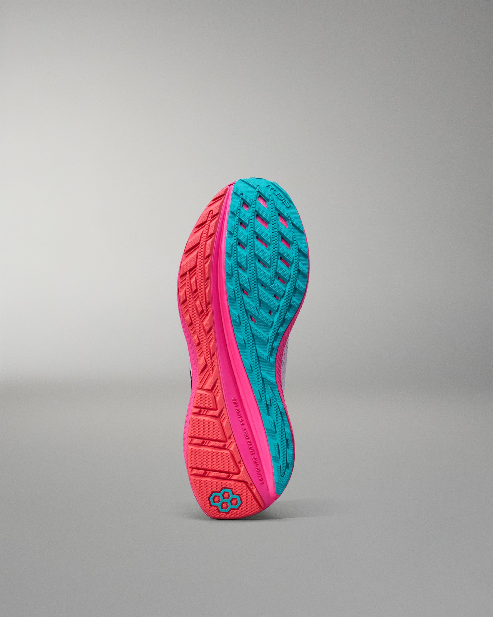 Close-up of a pink and teal athletic shoe sole on a gray background