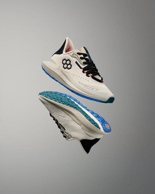 Pair of white training shoes with blue soles on a gray background