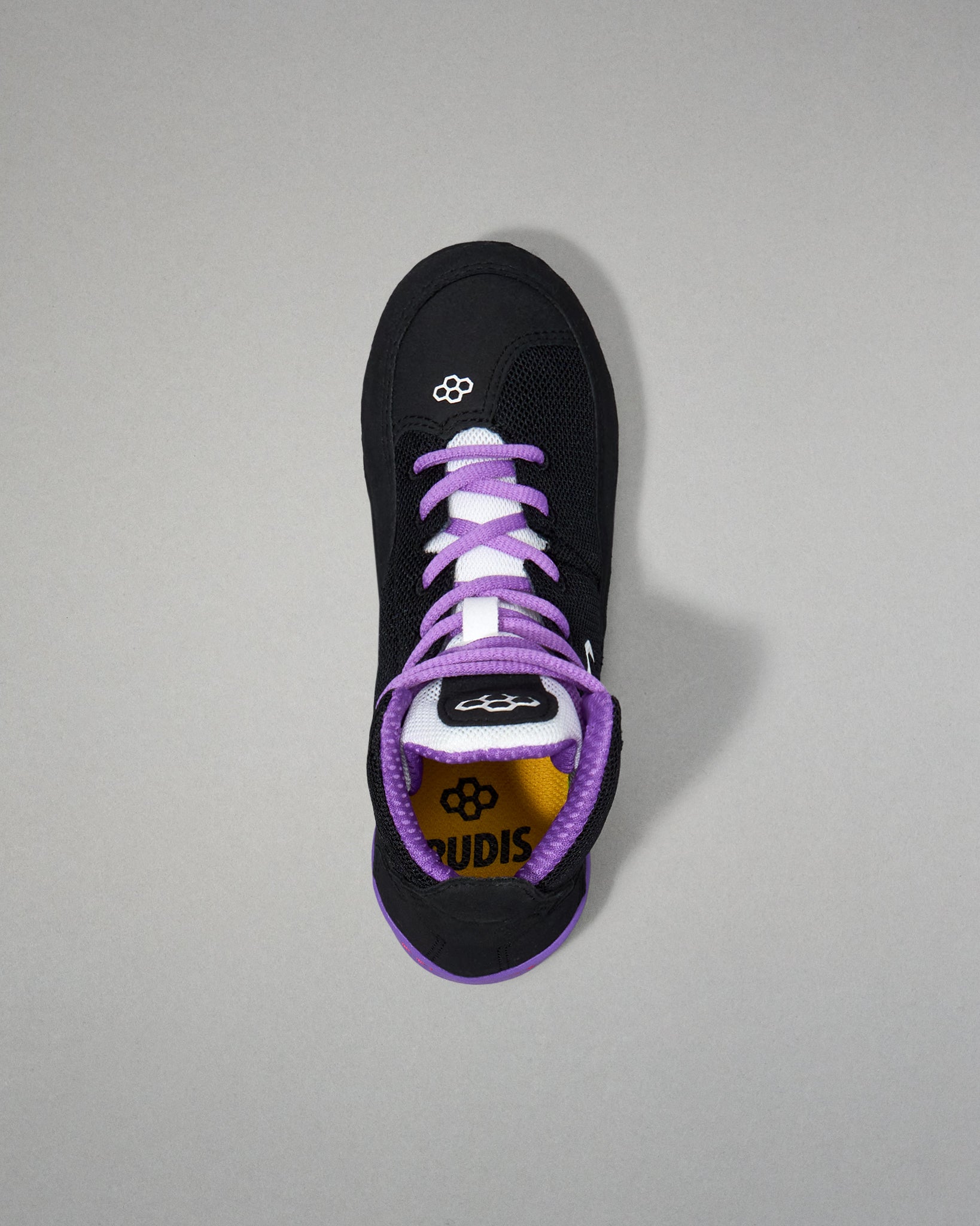 Black sneaker with purple laces on a gray background