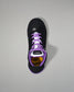 Black sneaker with purple laces on a gray background
