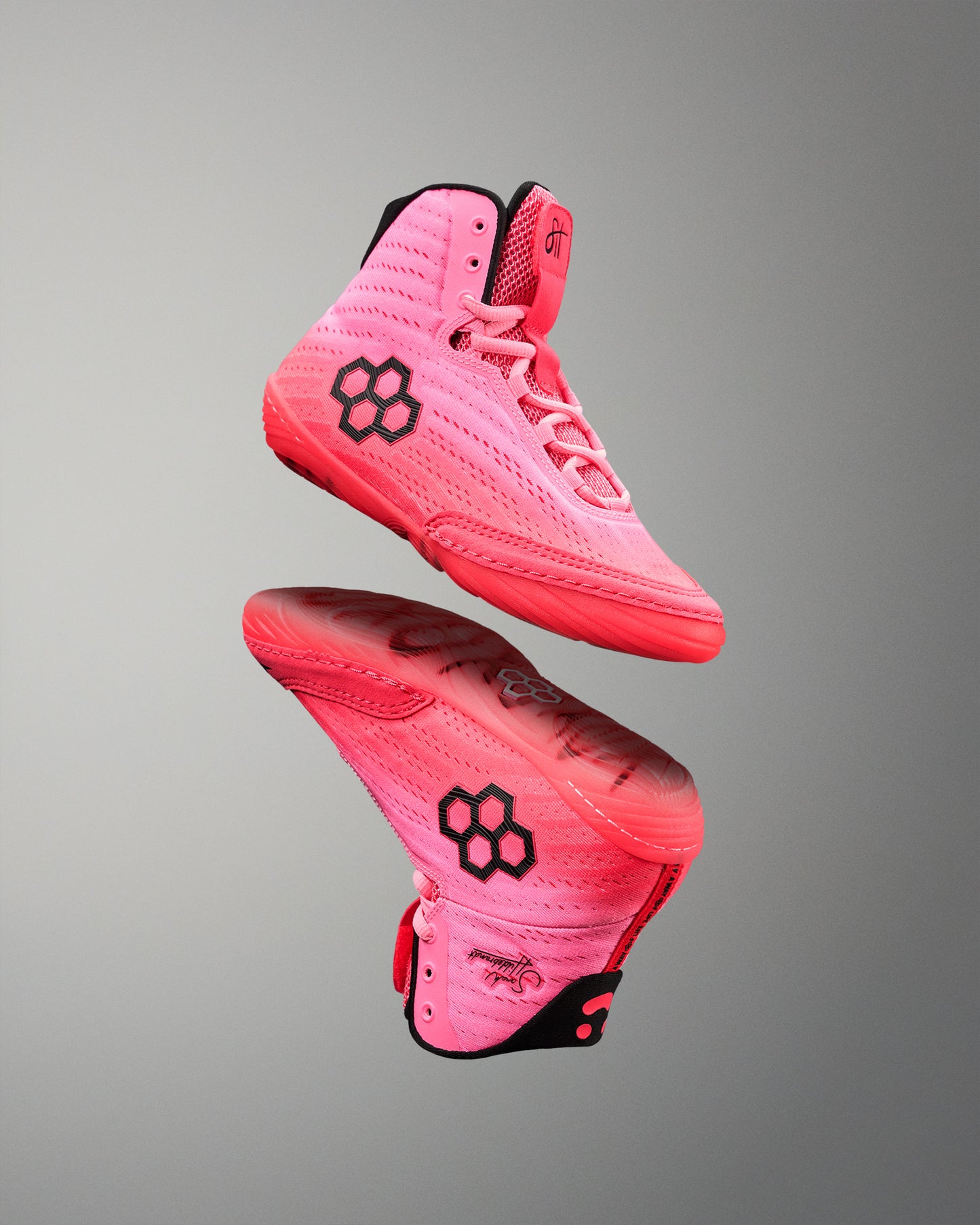 Pink wrestling shoes with a black logo on a gray background