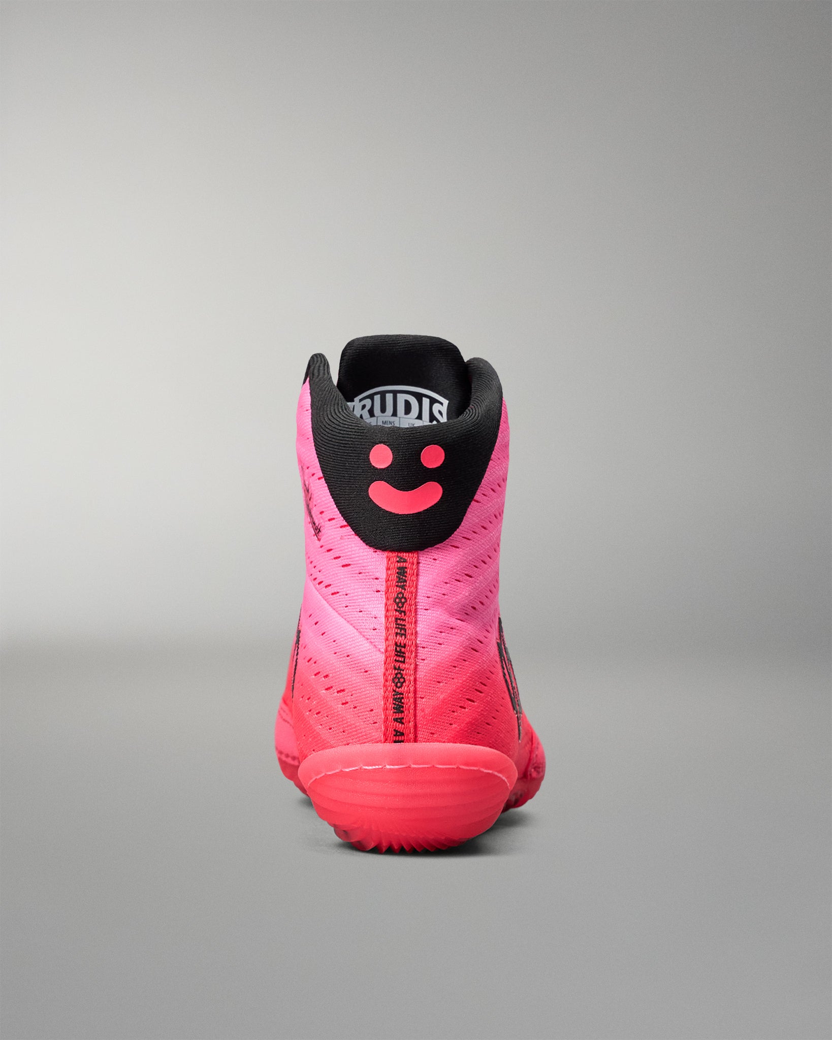 Pink and black wrestling shoe with a smiley face design on a gray background