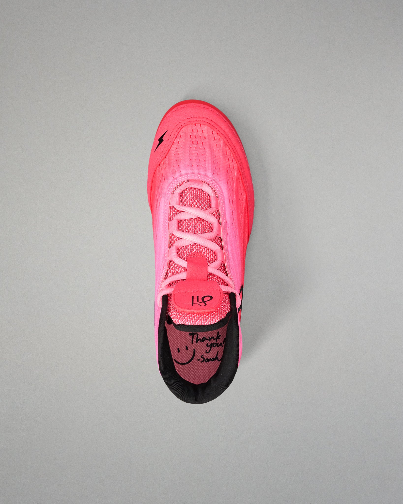 Pink wrestling shoe with black sole on a gray background