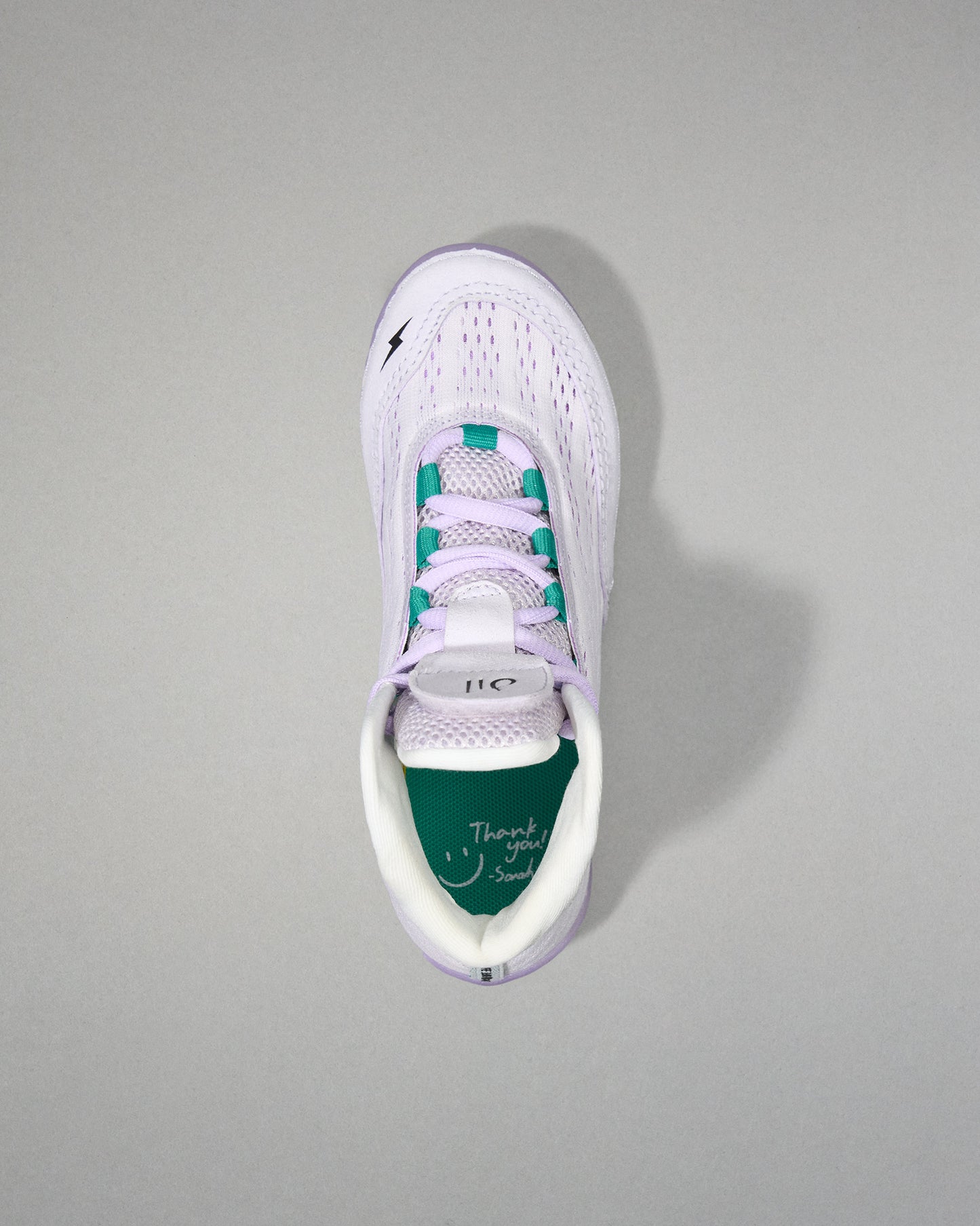 White sneaker with green sole on a gray background