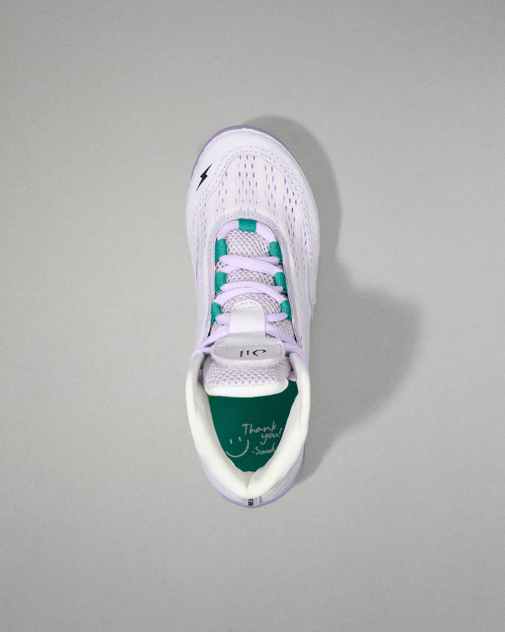 White sneaker with green sole on a gray background