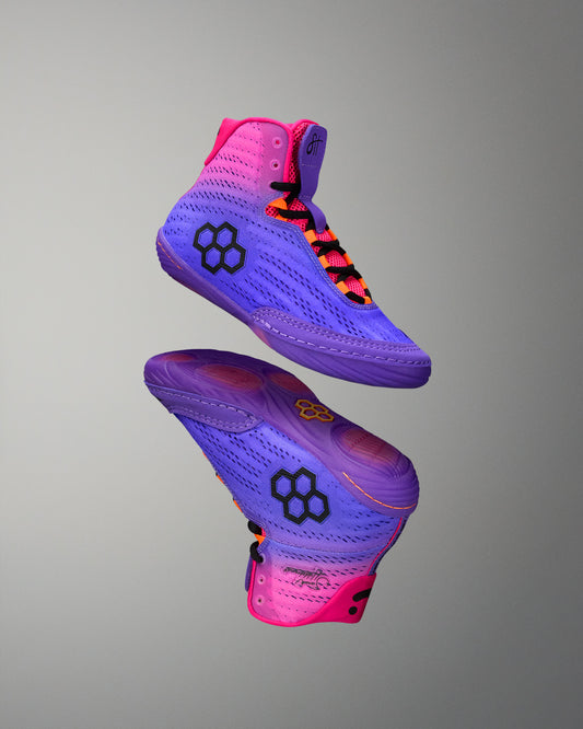Purple and pink wrestling shoes with a geometric design on a gray background