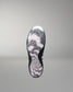A single wrestling shoe shown from the sole view, featuring a black outsole with a white, gray, and pink abstract wavy pattern, set against a neutral gray background.