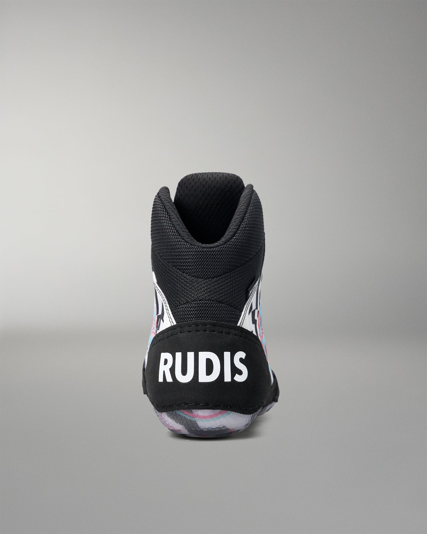 A black high-top wrestling shoe shown from the back, featuring a black heel counter with the brand name 'RUDIS' in bold white letters. The shoe has subtle pink and white graphic details on the sides and a translucent sole.