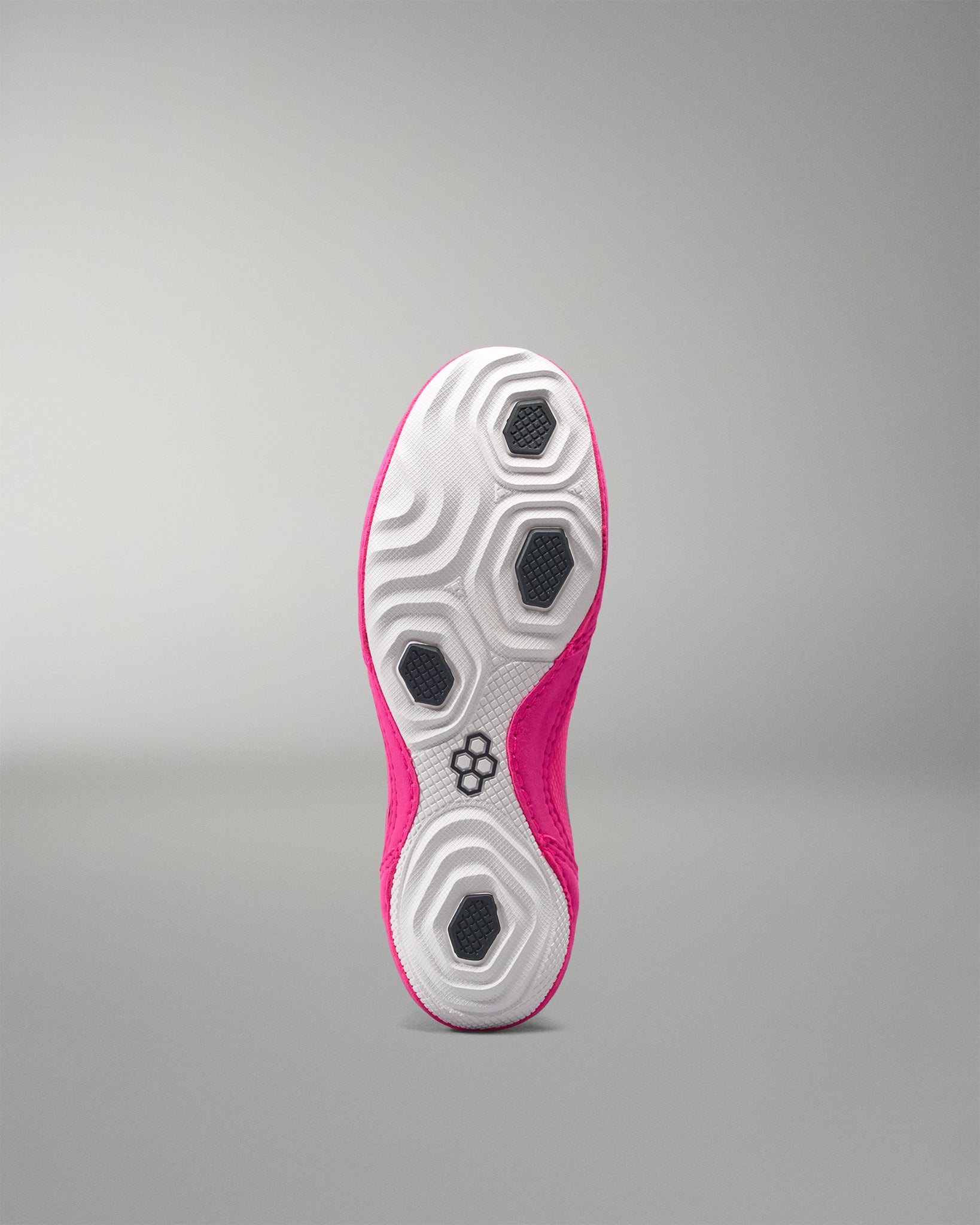 Sole of a pink and white athletic shoe on a gray background