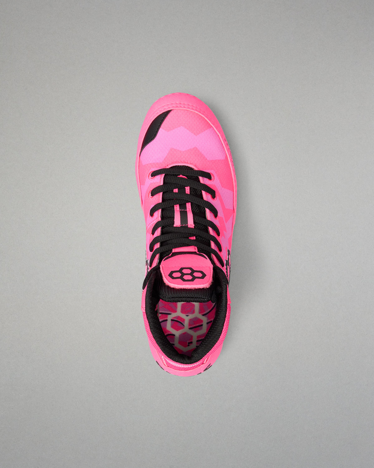 A single Wrestling shoe in vibrant pink with a geometric pattern, black laces, and black accents, photographed from a top-down perspective on a neutral gray background.