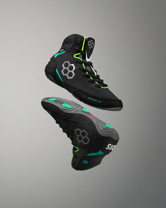 Black wrestling shoes with green accents on a gray background